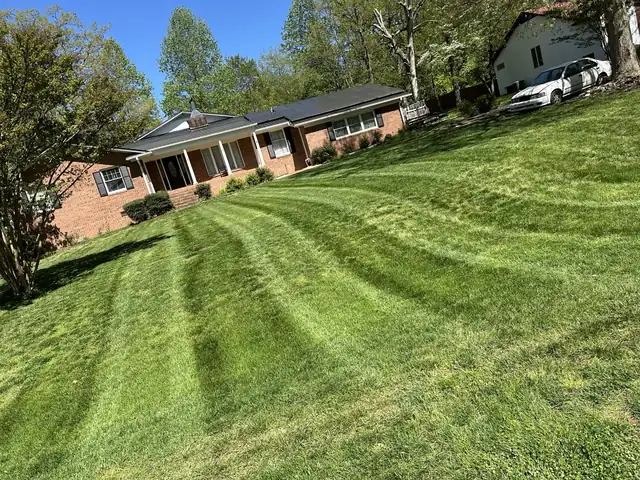 Freshly striped lawn in front of a brick home, maintained by Tiny Trail Landscaping