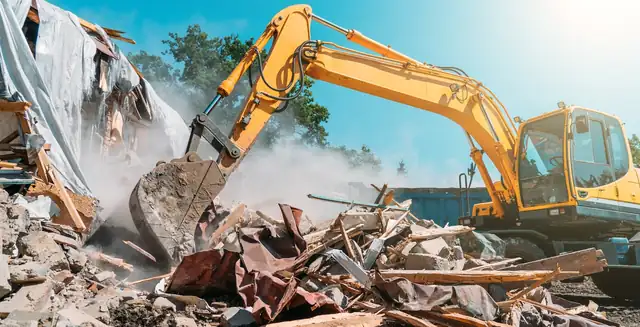 Excavator demolishing an old house