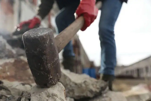 Worker breaking up concrete with a sledgehammer