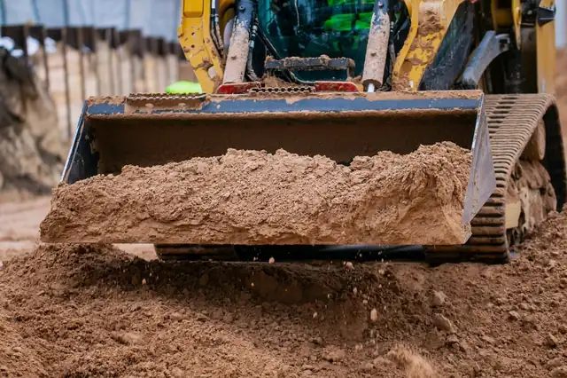 Track loader leveling ground to prepare a building site