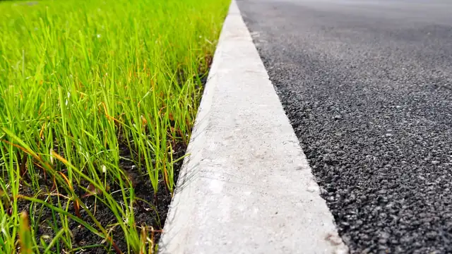 Clean edge where a paved surface meets a green lawn