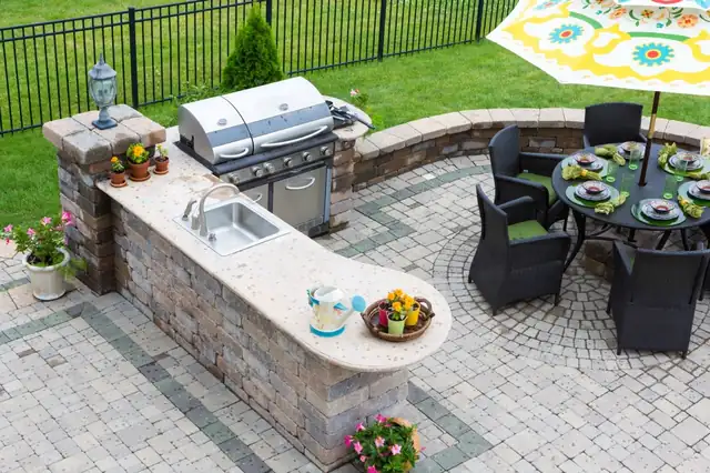 Outdoor kitchen and dining table on a paver patio