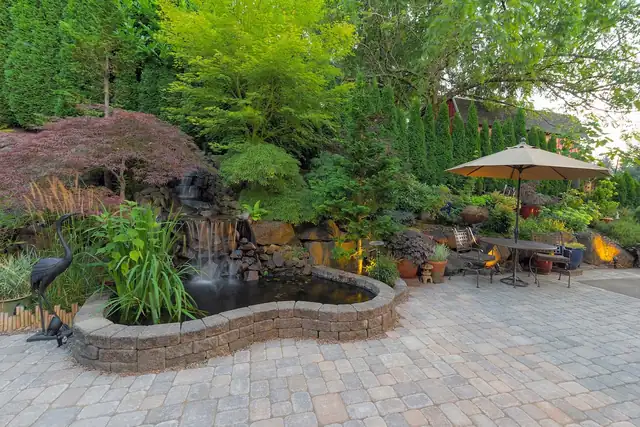Backyard paver patio with a waterfall pond